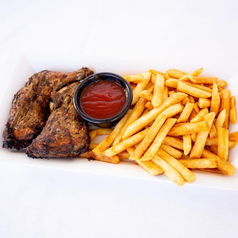 Ms. Martha's Caribbean Kitchen's jerk chicken with a side of golden french fries and ketchup.