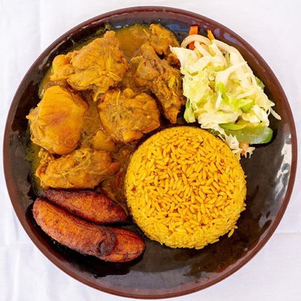 Ms. Martha's Caribbean Kitchen curry chicken, yellow rice, fried plantains, and coleslaw on a brown plate.