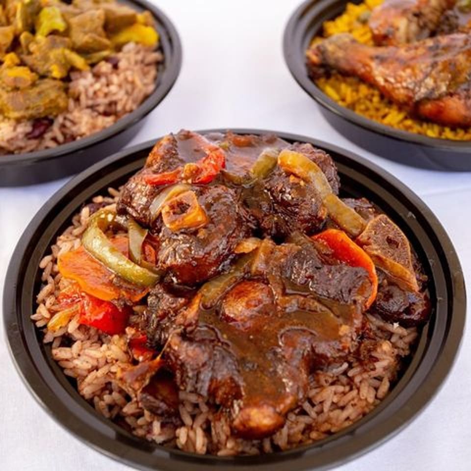 Ms. Martha's Caribbean Kitchen oxtail with rice and peas, with two other dishes blurred in the background.