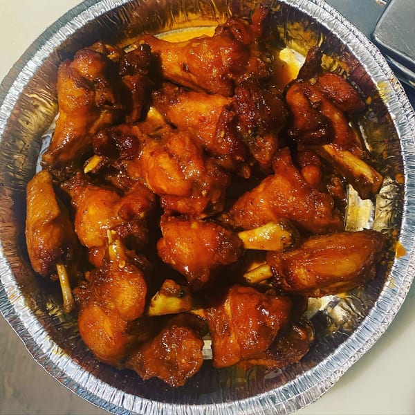Close-up of Ms. Martha's Caribbean Kitchen's glazed chicken wings in a foil container.