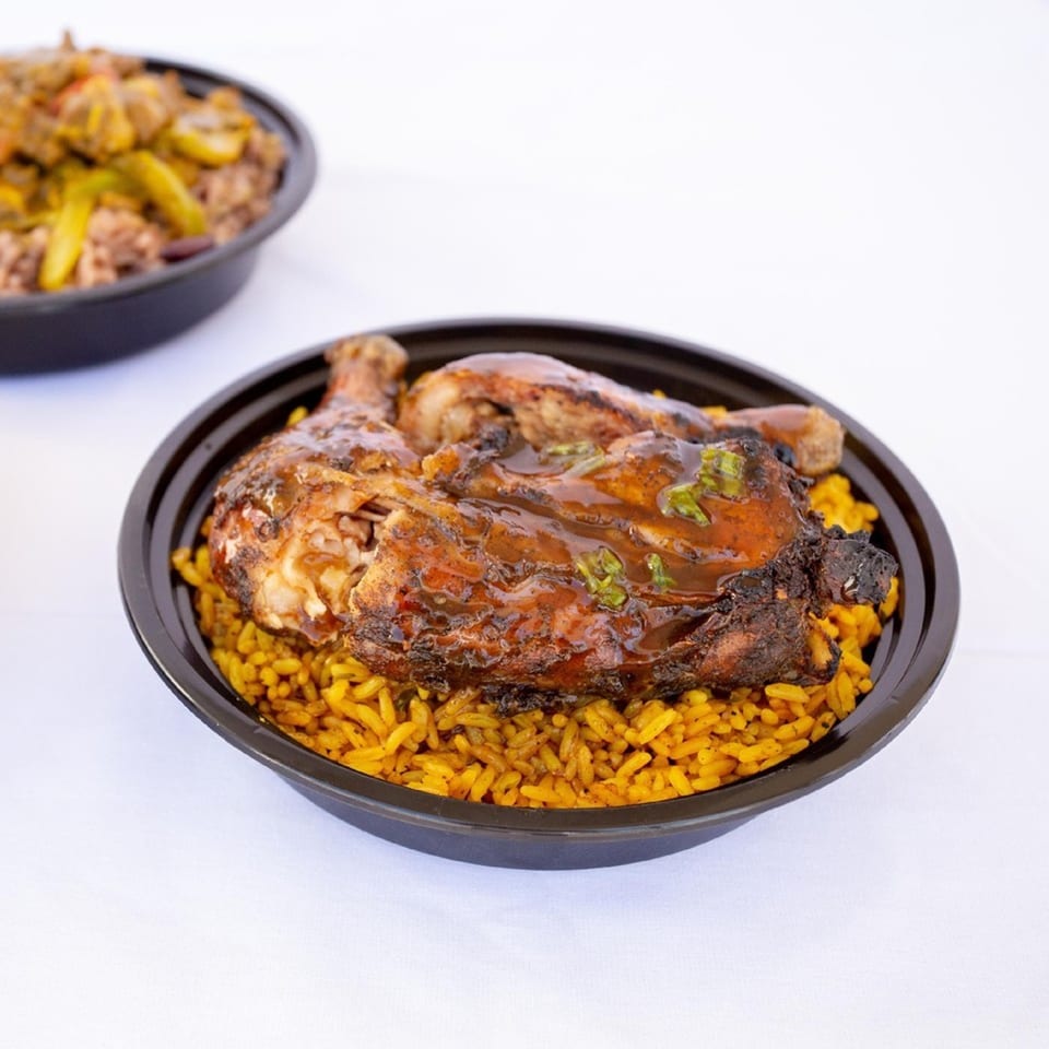 Ms. Martha's Caribbean Kitchen's jerk chicken with sauce and rice in a black bowl.